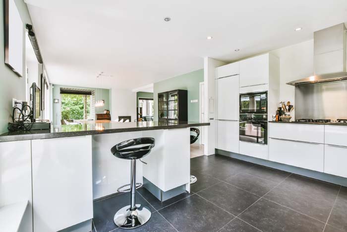The interior of a beautiful large kitchen with a white kitchen set and black chairs