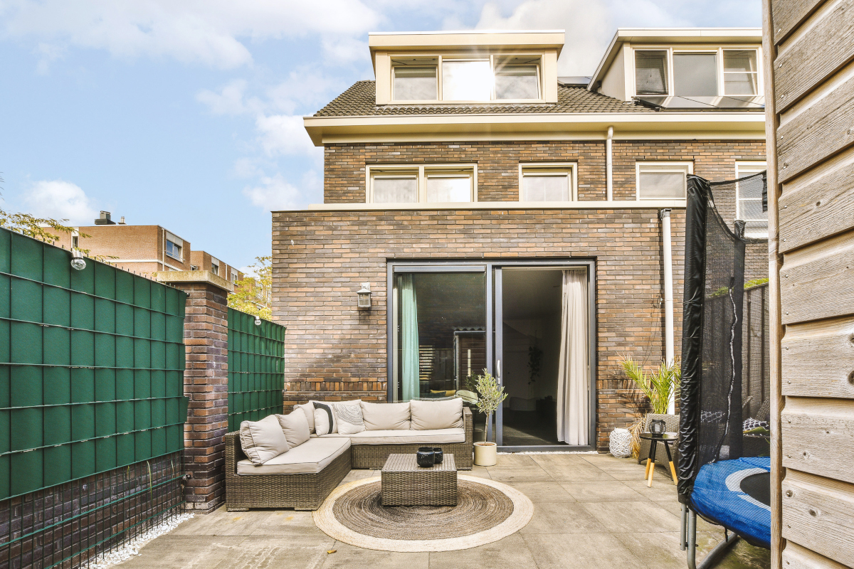 Neat paved patio with sitting area and small garden near wooden fence