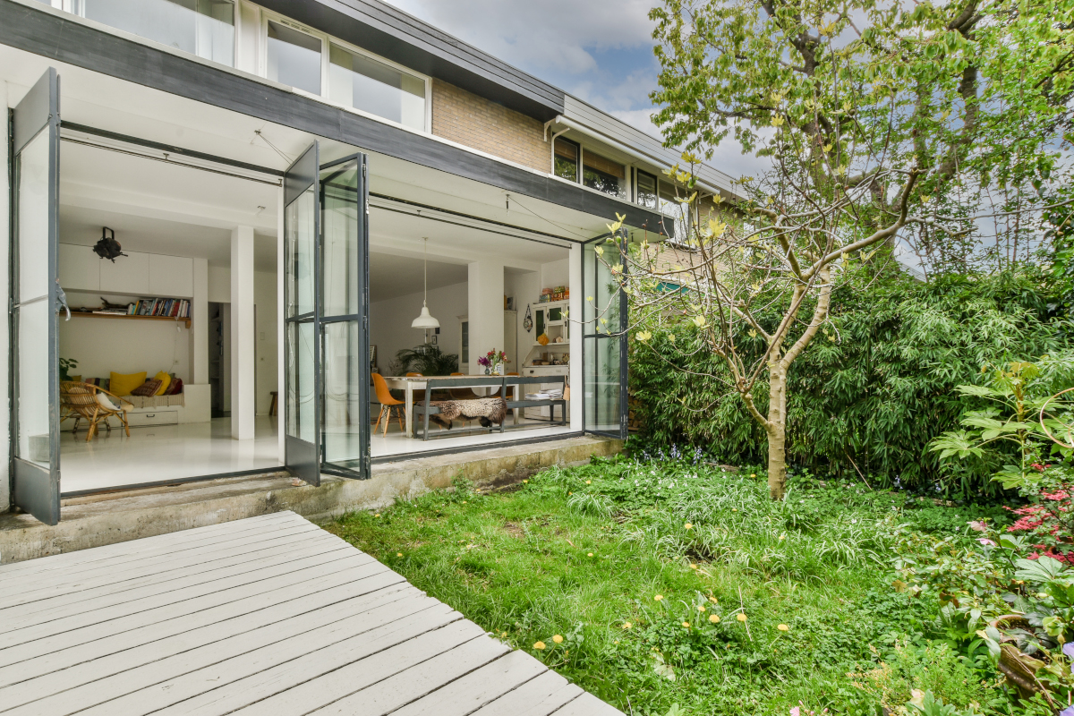 Neat paved patio with sitting area and small garden near wooden fence
