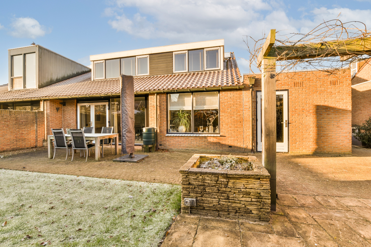 a brick house in the country style with an outdoor dining table and chairs set out on the front yard area